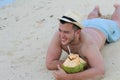 Ethnic male drinking a fresh coconut at the beach Royalty Free Stock Photo