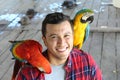 Ethnic man interacting with two gorgeous macaws Royalty Free Stock Photo