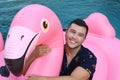 Ethnic man in large inflatable pink flamingo