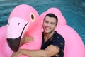 Ethnic man in large inflatable pink flamingo
