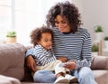 Ethnic mother and son using smartphone on sofa