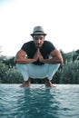 Ethnic stylish young man prying near a swimming pool