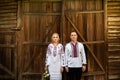 Ethnic wedding in national costumes. Ukrainian marriage bride and groom standing on the background of a wooden wall