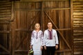 Ethnic wedding in national costumes. Ukrainian marriage bride and groom standing on the background of a wooden wall