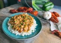 Homemade crawfish etouffee on a blue plate. Shown with whole boiled crawfish and garlic on a wood background.