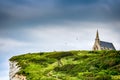 Etretat, France - June 29, 2012. Church on cliff by English Channel in Normandy with nature arches Royalty Free Stock Photo