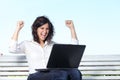 Euphoric businesswoman with a laptop sitting on a bench