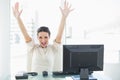 Euphoric stylish brunette businesswoman raising her arms