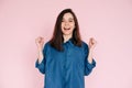 Euphoric Woman Celebrating Success, Raising Fists in Triumph: Isolated Pink Background Portrait. Joyful Woman