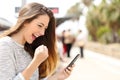 Euphoric woman watching her smart phone in a train station