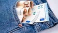 Euro bank notes in a back pocket of a navy blue denim jeans as a background composition