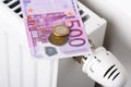 500 euro banknote with coins on heating radiator battery with thermostat temperature regulator Royalty Free Stock Photo