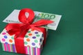 100 Euro banknote on a gift box with a red bow. Green background Royalty Free Stock Photo