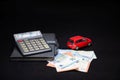 euro banknotes, calculator, notebook and red toy car on black background, insurance and loan concept Royalty Free Stock Photo