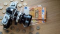 Euro banknotes, coins and a camera on a light wooden background. Royalty Free Stock Photo