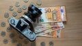 Euro banknotes, coins and a camera on a light wooden background. Royalty Free Stock Photo