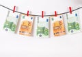 Euro banknotes hanging on a clothesline against white background. Euro money with red clothes pegs on rope. Money Laundering euro Royalty Free Stock Photo