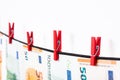 Euro banknotes hanging on a clothesline against white background. Euro money with red clothes pegs on rope. Money Laundering euro Royalty Free Stock Photo