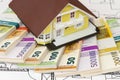 Euro banknotes laying under model home