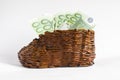 Euro banknotes lie in an old wooden boot.