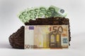 Euro banknotes lie in an old wooden boot.