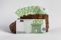 Euro banknotes lie in an old wooden boot.