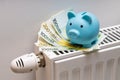 100 and 200 Euro banknotes lying on the radiator together with a small blue piggy bank, The concept of rising costs of heating an Royalty Free Stock Photo