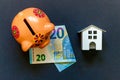 Toy House, piggy bank and euro on black background Royalty Free Stock Photo