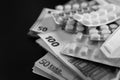 Euro banknotes and pills, on black background, concept of treatment costs, paid medicine, tranche of the International Monetary Royalty Free Stock Photo