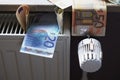 euro banknotes on radiator as concept for rising heating costs and gas price crisis