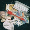 Euro banknotes and red arrow symbol, disposable face mask, syringes, medical gloves. Healthcare and financial crisis