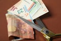 Euro banknotes and scissors on brown background, closeup Royalty Free Stock Photo