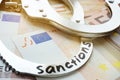 Euro bills and handcuffs with sanctions. Economical restrictive measures.