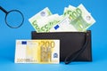 100 200 euro bills and magnifying glass with black wallet. Concept of counterfeit money. The concept of cash cash savings