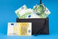 100 200 euro bills and magnifying glass with black wallet. Concept of counterfeit money. The concept of cash cash savings