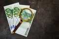 100 euro bills and magnifying glass close-up on dark stone background Royalty Free Stock Photo