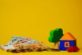 Euro cash money euro coins and banknotes with wood toy house, tree and auto on yellow background. Property Ownership Royalty Free Stock Photo