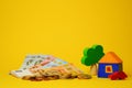 Euro cash money euro coins and banknotes with wood toy house, tree and auto on yellow background. Property Ownership Royalty Free Stock Photo