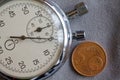 Euro coin with a denomination of 5 euro cents and stopwatch on gray denim backdrop - business background Royalty Free Stock Photo