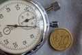 Euro coin with a denomination of 10 euro cents and stopwatch on gray denim backdrop - business background Royalty Free Stock Photo