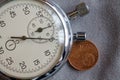 Euro coin with a denomination of 2 euro cents and stopwatch on gray denim backdrop - business background Royalty Free Stock Photo