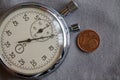 Euro coin with a denomination of one euro cent and stopwatch on gray denim backdrop - business background Royalty Free Stock Photo