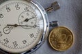 Euro coin with a denomination of 20 euro cents and stopwatch on gray denim backdrop - business background Royalty Free Stock Photo