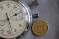 Euro coin with a denomination of ten euro cents (back side) and stopwatch on gray denim backdrop - business background Royalty Free Stock Photo