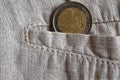 Euro coin with a denomination of 2 euros in the pocket of worn linen pants