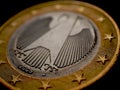 1 euro coin issued in Germany close-up. Obverse with the Federal Eagle. Dark dramatic economic background or backdrop. European