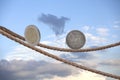 2 Euro coin and one dollar coin balancing on rope Royalty Free Stock Photo