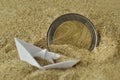 Euro coin and paper boat sinking in the sand - Concept of immigration