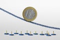 Euro coin on rope over push pins - Concept of downward trend of euro currency and euro currency risk Royalty Free Stock Photo