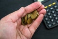 Euro coins cents in a palm and a calculator on a black background. Concept of saving or saving money. Royalty Free Stock Photo